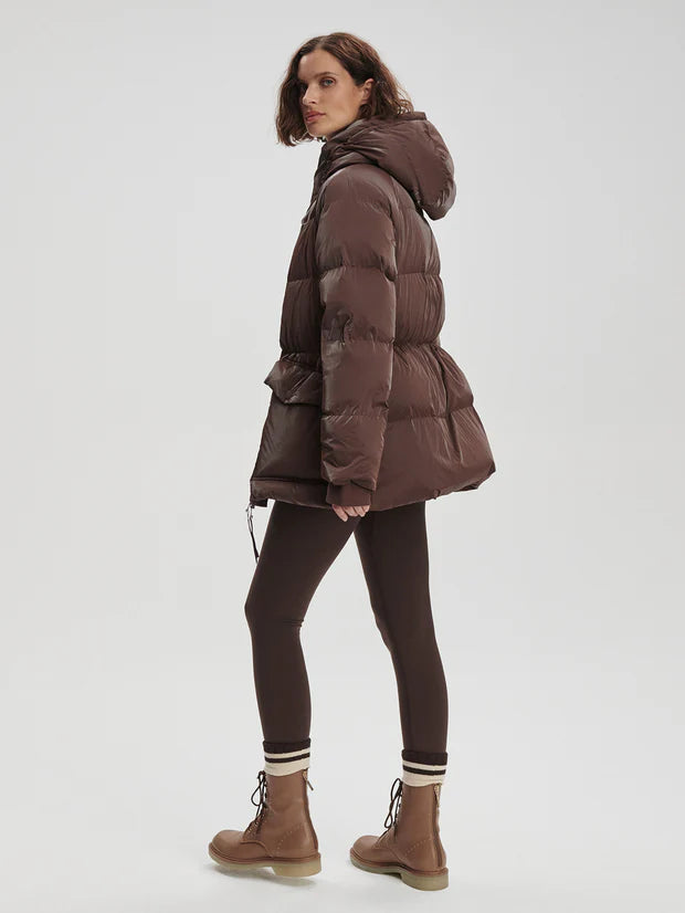 Person wearing a brown winter coat, leggings, and boots 