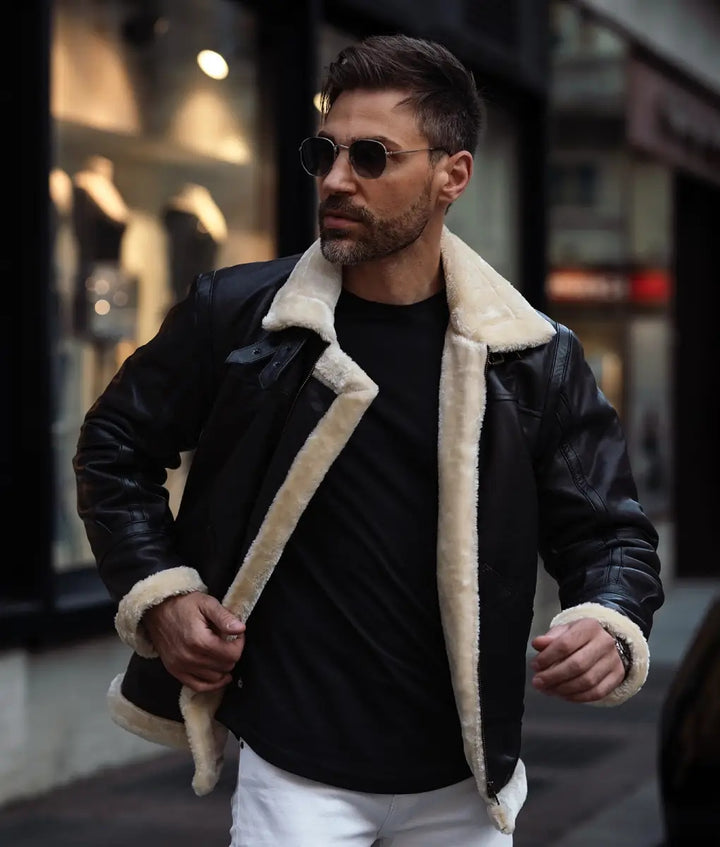 Man wearing a black leather jacket with white fur trim in an urban setting