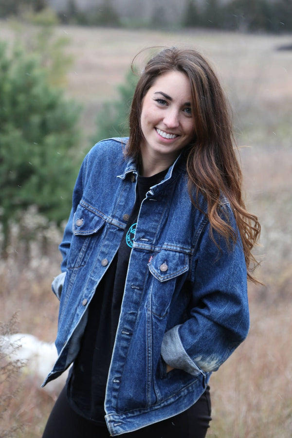Front view of vintage blue denim jacket with button closure and folded cuffs